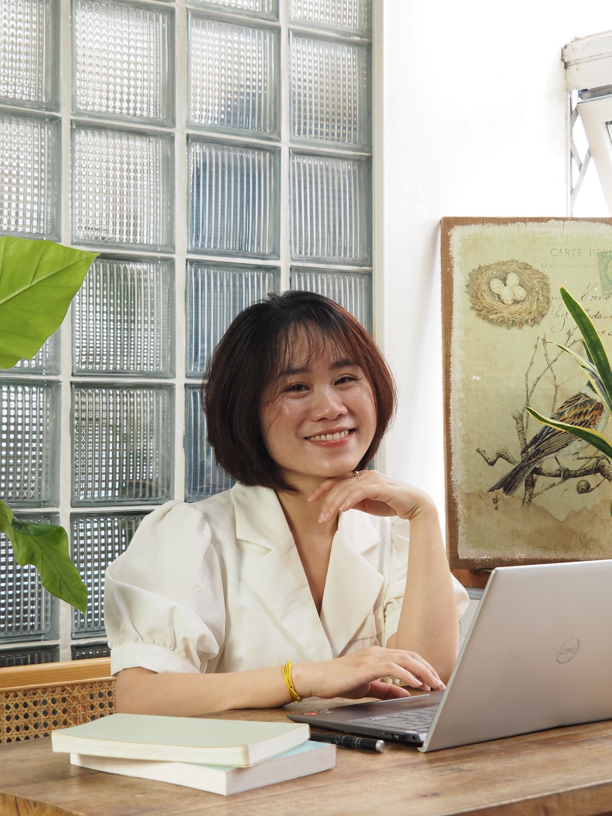 Hoa ngồi bên bàn làm việc, mỉm cười