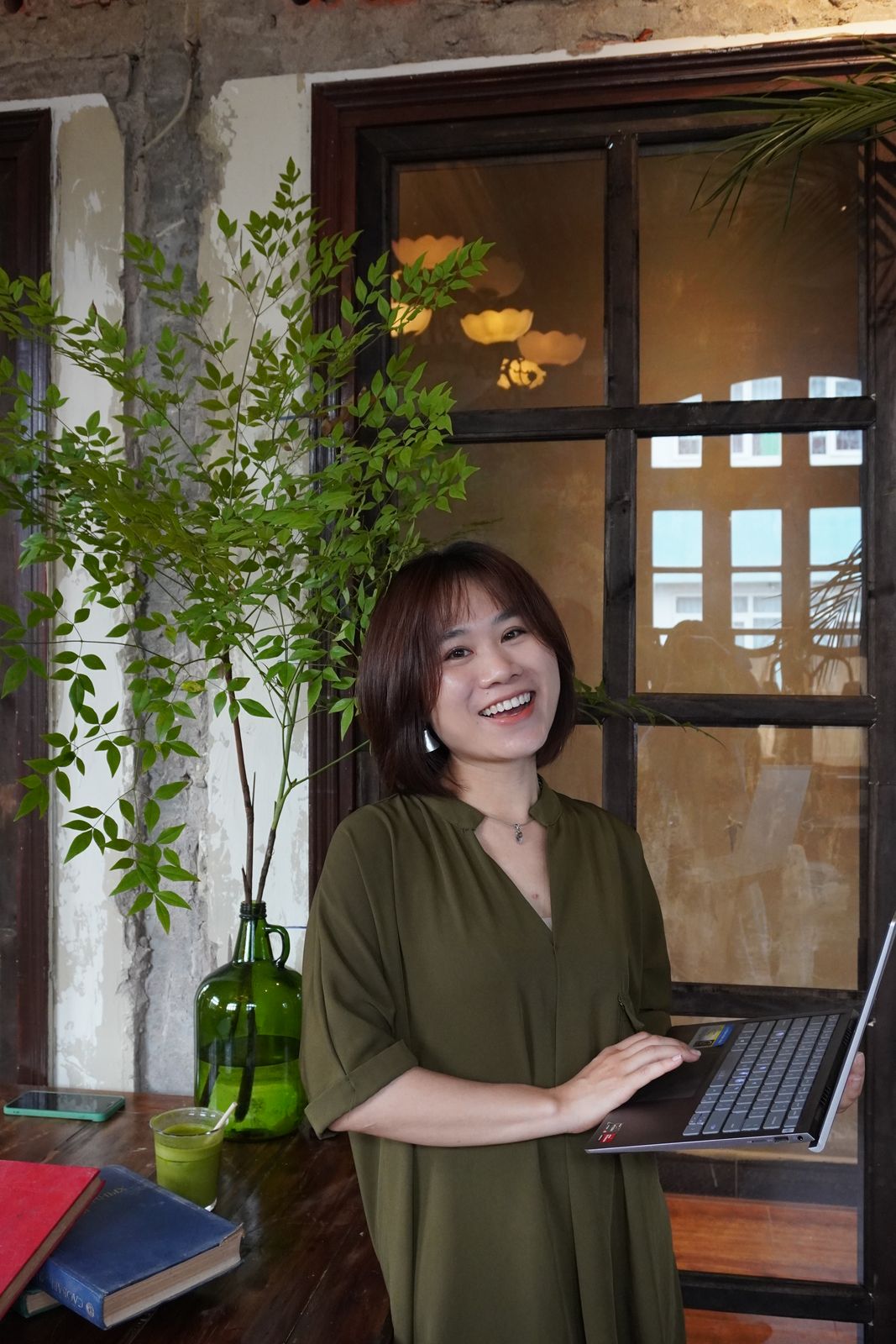 Hoa đứng bên laptop, cười rạng rỡ