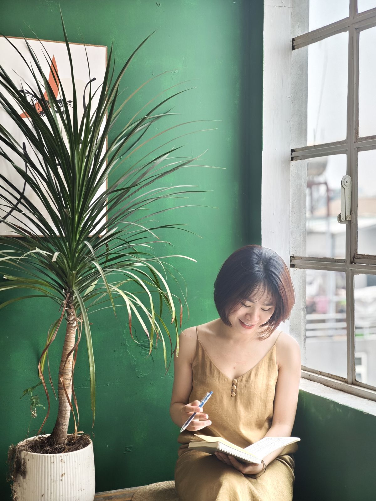 Hoa ngồi viết journal bên cửa sổ